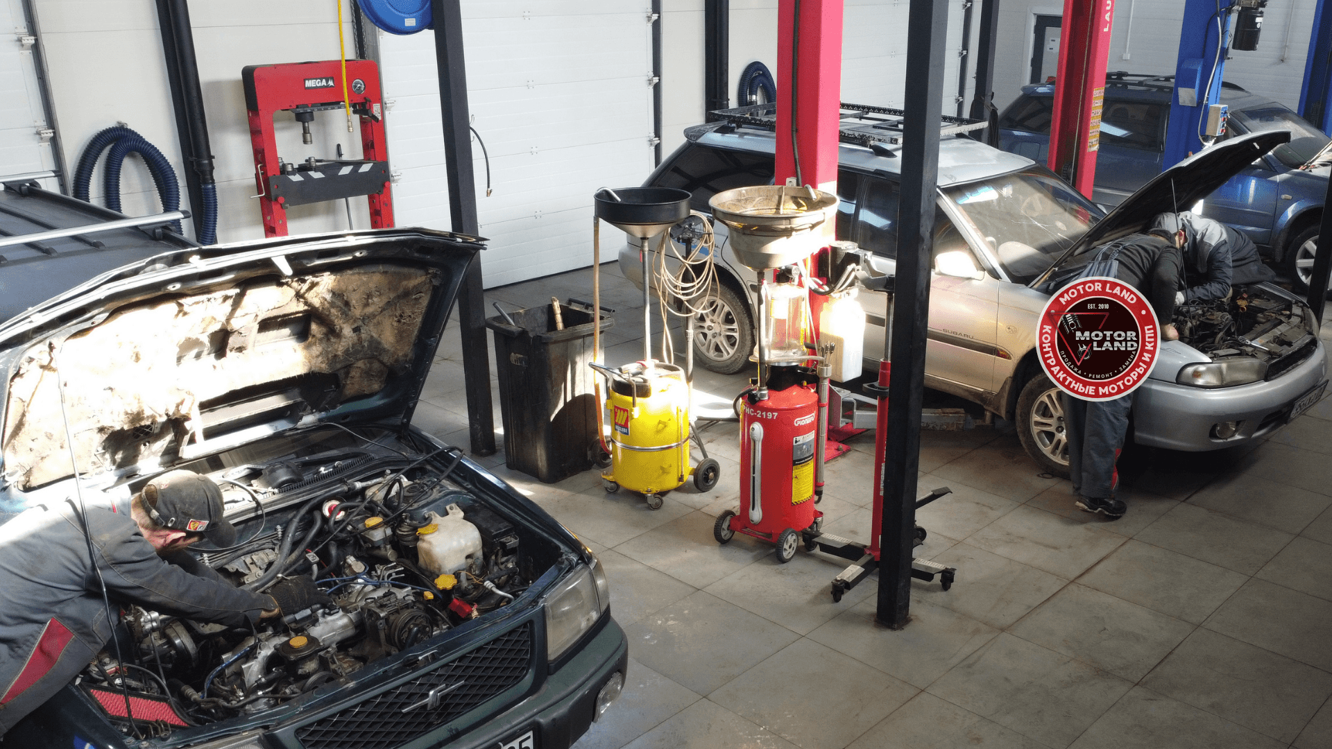 Мастер работает под капотом автомобиля в автосервисе Motor Land